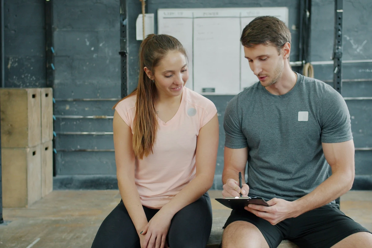 Personal Trainer bespricht einen Trainingsplan mit einer Kundin
