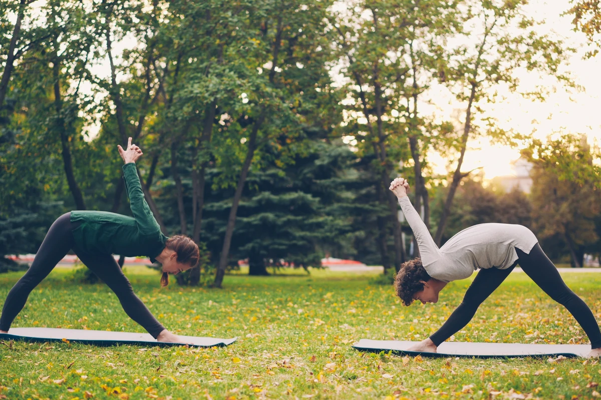 Zwei Personen bei einer realistischen Yoga-Session im Park